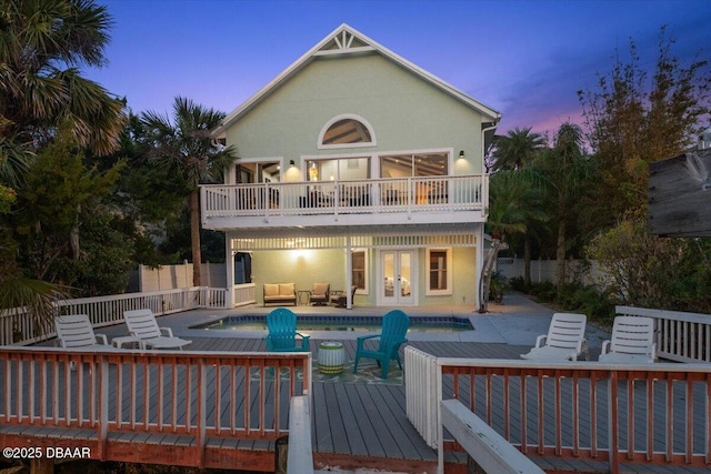 3110 John Anderson Dr, Ormond Beach, FL 32176 - back house at dusk with a balcony, french doors, outdoor lounge area, a pool side deck, and a patio area