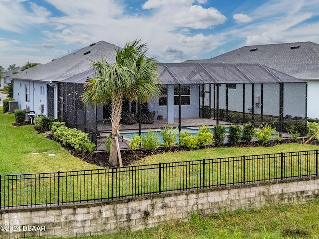 rear view of house featuring a lanai, a pool, and a lawn