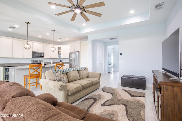 living room with ceiling fan and a tray ceiling