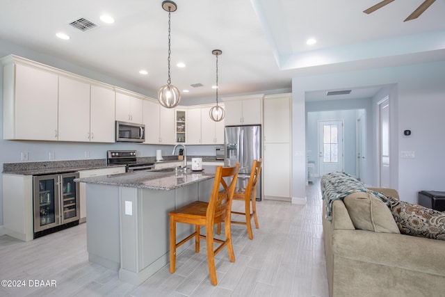 kitchen with wine cooler, decorative light fixtures, sink, an island with sink, and stainless steel appliances