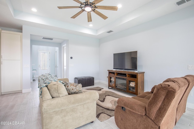 living room with ceiling fan, light hardwood / wood-style flooring, and a raised ceiling