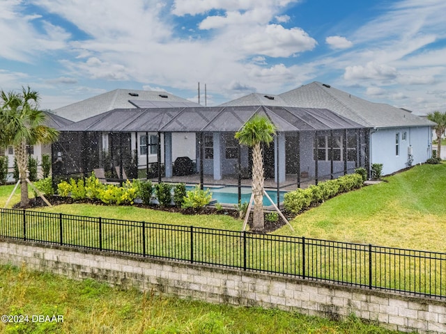 back of house featuring a lanai, a fenced in pool, and a yard