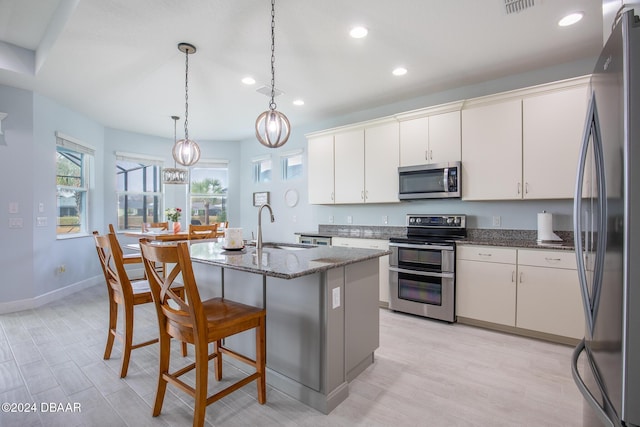 kitchen featuring a center island with sink, appliances with stainless steel finishes, white cabinets, and sink