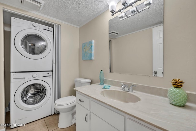 3824 Saxon Dr, New Smyrna Beach, FL 32169 - bathroom with stacked washer and clothes dryer, tile patterned flooring, vanity, and a textured ceiling