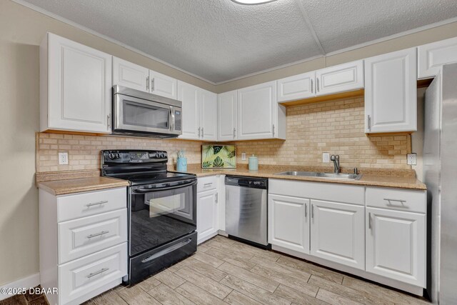 3824 Saxon Dr, New Smyrna Beach, FL 32169 - kitchen with stainless steel appliances, light countertops, white cabinets, ornamental molding, and a textured ceiling