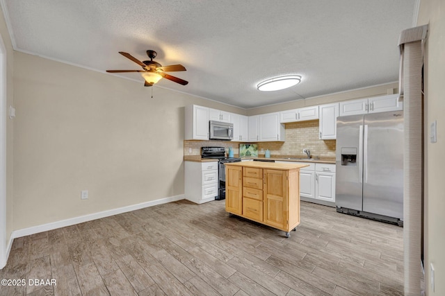 3824 Saxon Dr, New Smyrna Beach, FL 32169 - kitchen featuring stainless steel appliances, light wood-style floors, ceiling fan, a textured ceiling, and tasteful backsplash