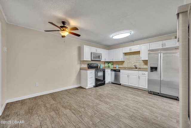 3824 Saxon Dr, New Smyrna Beach, FL 32169 - kitchen featuring appliances with stainless steel finishes, light countertops, light wood-style flooring, ceiling fan, and a textured ceiling