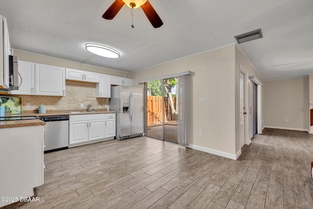 3824 Saxon Dr, New Smyrna Beach, FL 32169 - kitchen with stainless steel appliances, a textured ceiling, white cabinets, light wood finished floors, and a ceiling fan