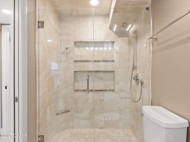 bathroom featuring toilet and a shower with shower door