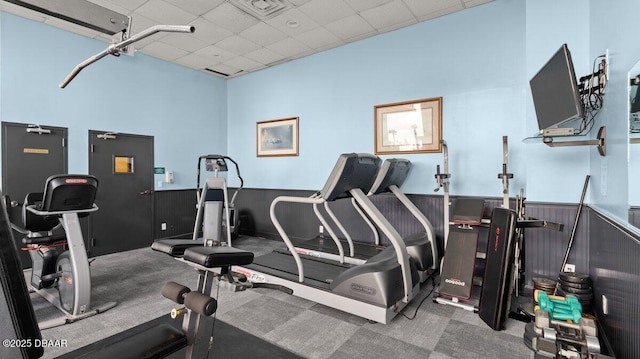 exercise room with a paneled ceiling and carpet