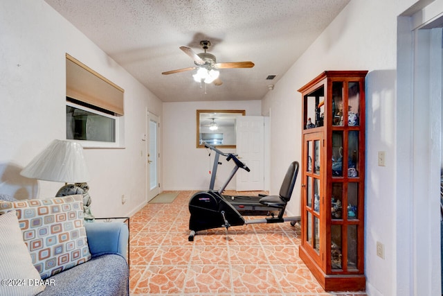 workout area with ceiling fan and a textured ceiling