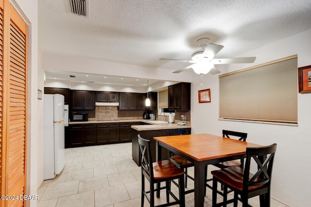 kitchen with white refrigerator, sink, dark brown cabinetry, and backsplash