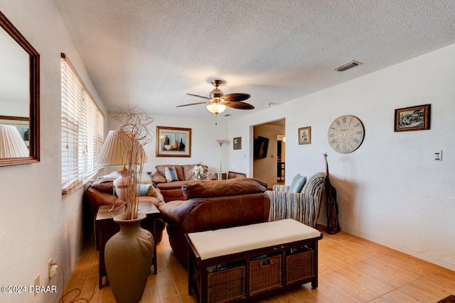 living room with ceiling fan, light hardwood / wood-style floors, and a textured ceiling