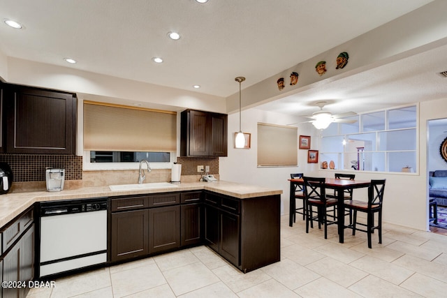 kitchen with decorative backsplash, dishwasher, hanging light fixtures, and sink