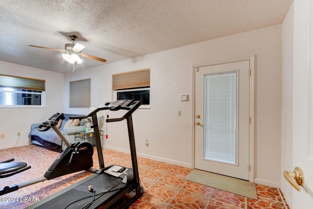 exercise area featuring ceiling fan and a textured ceiling