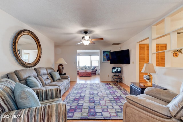 living room featuring a textured ceiling, hardwood / wood-style flooring, and ceiling fan