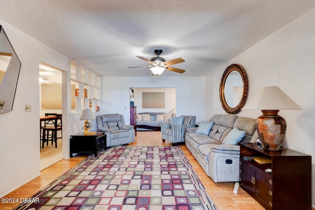 living room with ceiling fan, hardwood / wood-style floors, and a textured ceiling