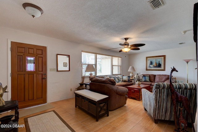 living room with ceiling fan, light hardwood / wood-style floors, and a textured ceiling