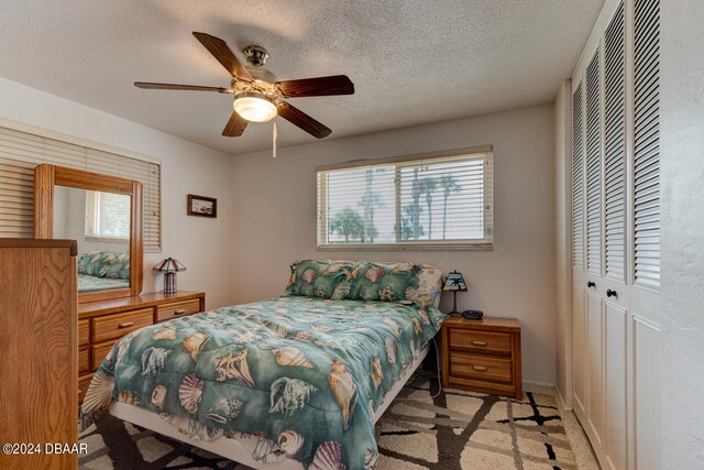 carpeted bedroom featuring ceiling fan, a textured ceiling, and multiple windows