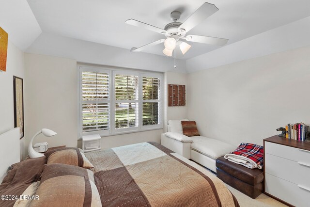 carpeted bedroom with a tray ceiling and ceiling fan