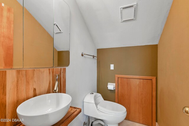 bathroom featuring tile patterned floors, sink, vaulted ceiling, and toilet