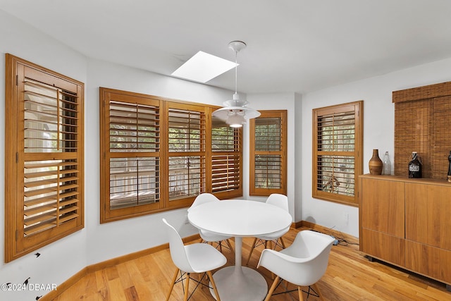 dining room featuring a skylight and light hardwood / wood-style flooring