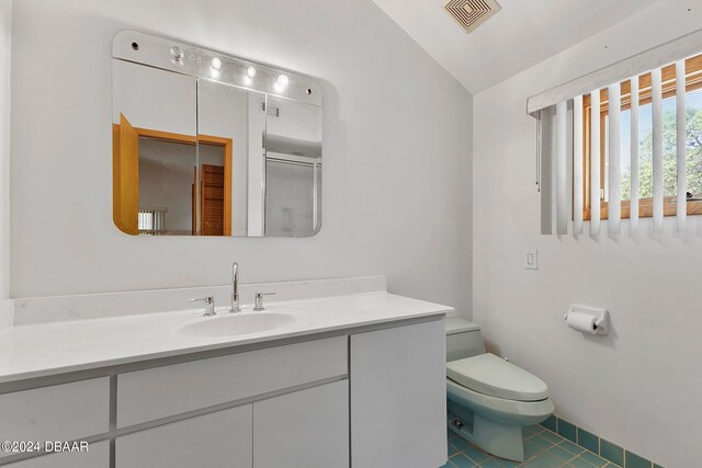 bathroom featuring tile patterned floors, toilet, vaulted ceiling, vanity, and a shower with shower door