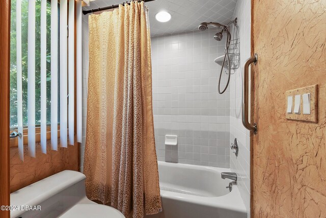 bathroom with toilet, a healthy amount of sunlight, and shower / bathtub combination with curtain