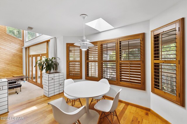 dining area with light wood-type flooring, a skylight, and plenty of natural light