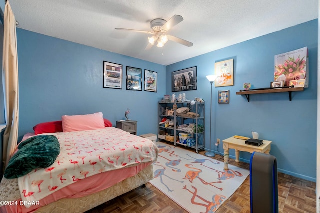 bedroom with dark parquet flooring, ceiling fan, and a textured ceiling