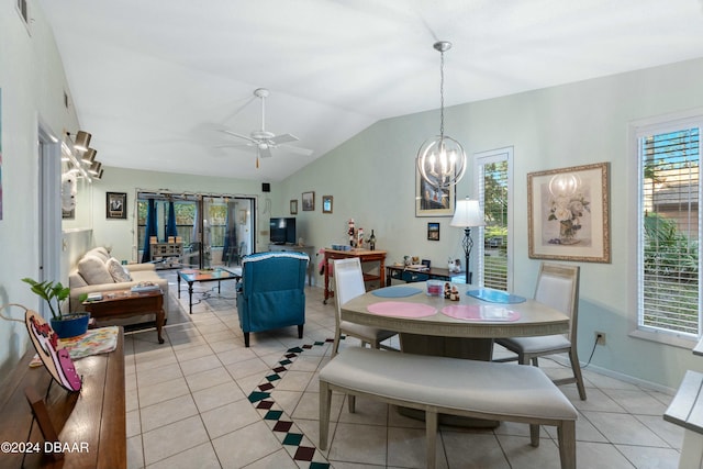 dining space with ceiling fan with notable chandelier, light tile patterned floors, and vaulted ceiling