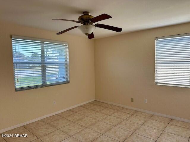 tiled spare room featuring ceiling fan and plenty of natural light