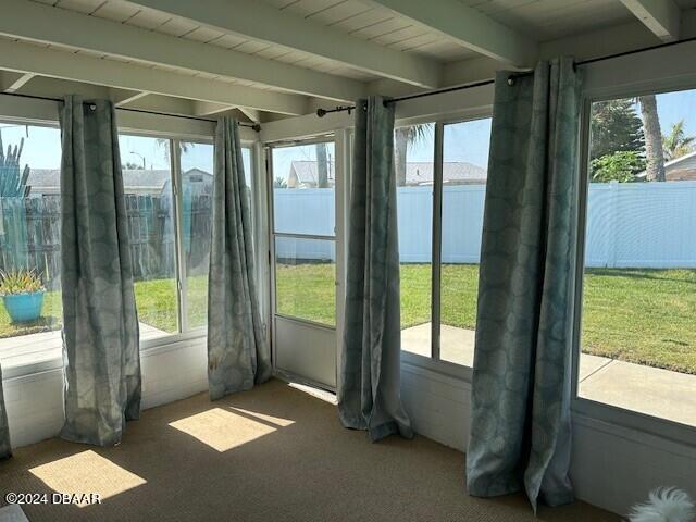 unfurnished sunroom with beamed ceiling and a healthy amount of sunlight