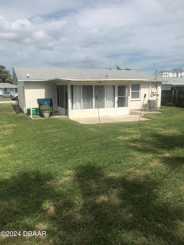 back of house with central air condition unit, a sunroom, and a yard