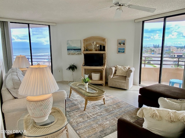 living room featuring a textured ceiling, light wood-type flooring, a healthy amount of sunlight, and floor to ceiling windows