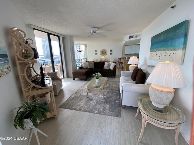 living room featuring floor to ceiling windows, a textured ceiling, ceiling fan with notable chandelier, and light hardwood / wood-style flooring