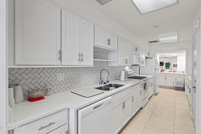 kitchen featuring white cabinets, sink, light tile patterned flooring, backsplash, and white appliances