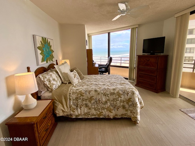 bedroom with a textured ceiling, light wood-type flooring, ceiling fan, and floor to ceiling windows