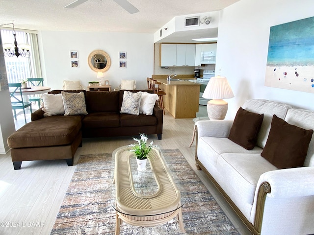 living room featuring a textured ceiling, sink, light hardwood / wood-style floors, and ceiling fan with notable chandelier