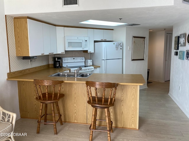 kitchen with white cabinetry, white appliances, and kitchen peninsula