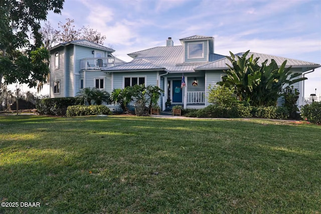 21951 Tarragona Way, Astor, FL 32102 - view of front facade featuring a front lawn, metal roof, a chimney, and a balcony