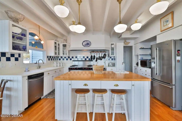 21951 Tarragona Way, Astor, FL 32102 - kitchen with appliances with stainless steel finishes, a sink, white cabinetry, a kitchen island, and beamed ceiling