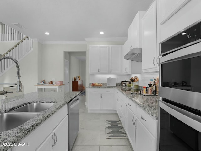 kitchen with appliances with stainless steel finishes, sink, white cabinets, and backsplash