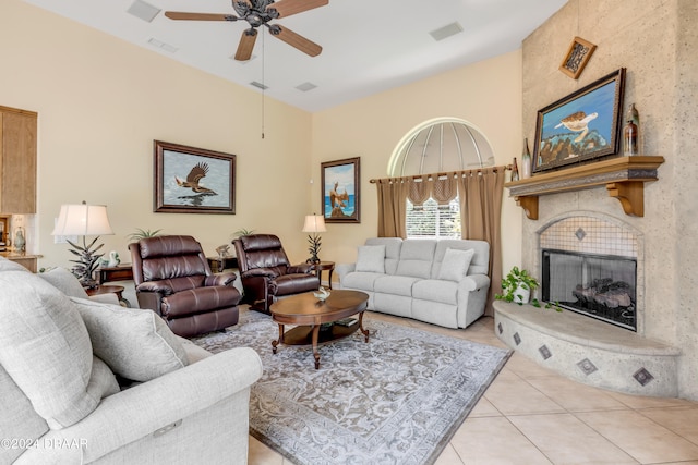 tiled living room featuring a fireplace and ceiling fan