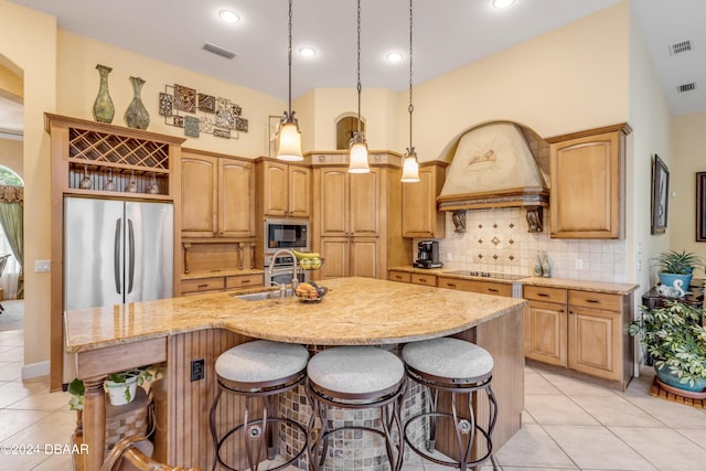 kitchen with decorative light fixtures, an island with sink, light tile patterned flooring, and stainless steel appliances