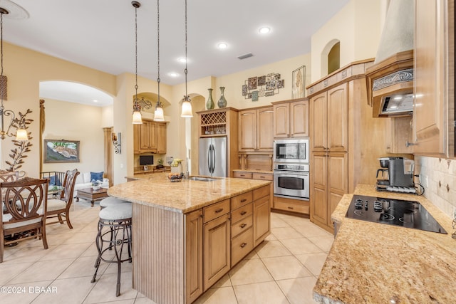 kitchen with hanging light fixtures, a kitchen island with sink, and appliances with stainless steel finishes