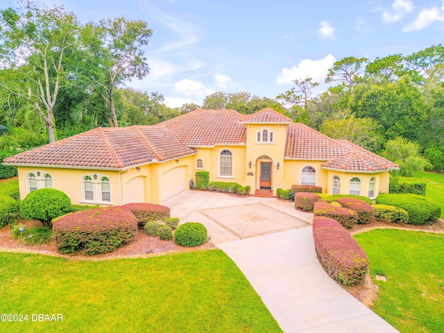 mediterranean / spanish home featuring a garage and a front lawn