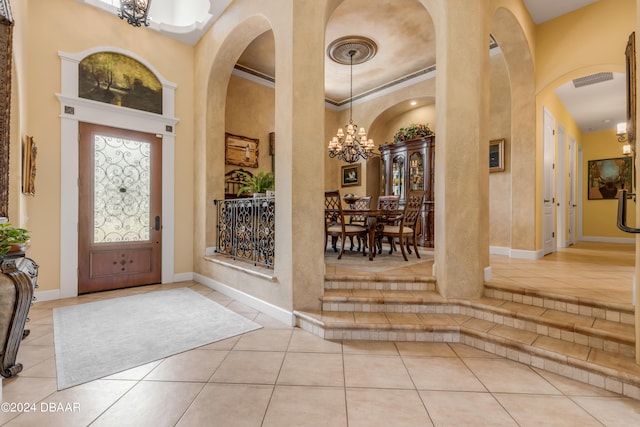 tiled entrance foyer with a high ceiling, an inviting chandelier, and ornamental molding