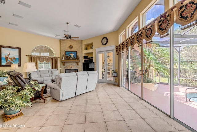 living room featuring french doors, a fireplace, light tile patterned floors, and ceiling fan