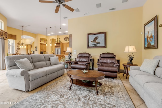 tiled living room with ceiling fan with notable chandelier